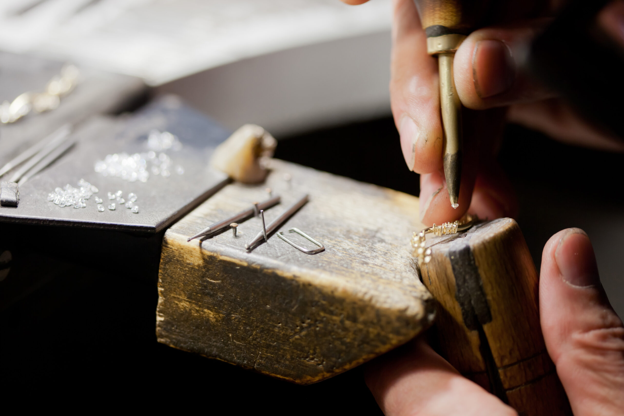 jeweller hands working with tools bending and polishing golden metal jewellery decoration, closeup