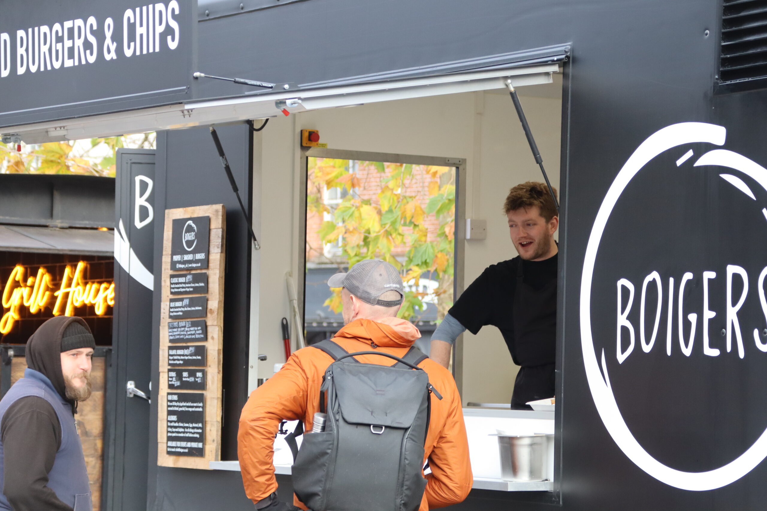 Man serving food to a customer from a food van window.
