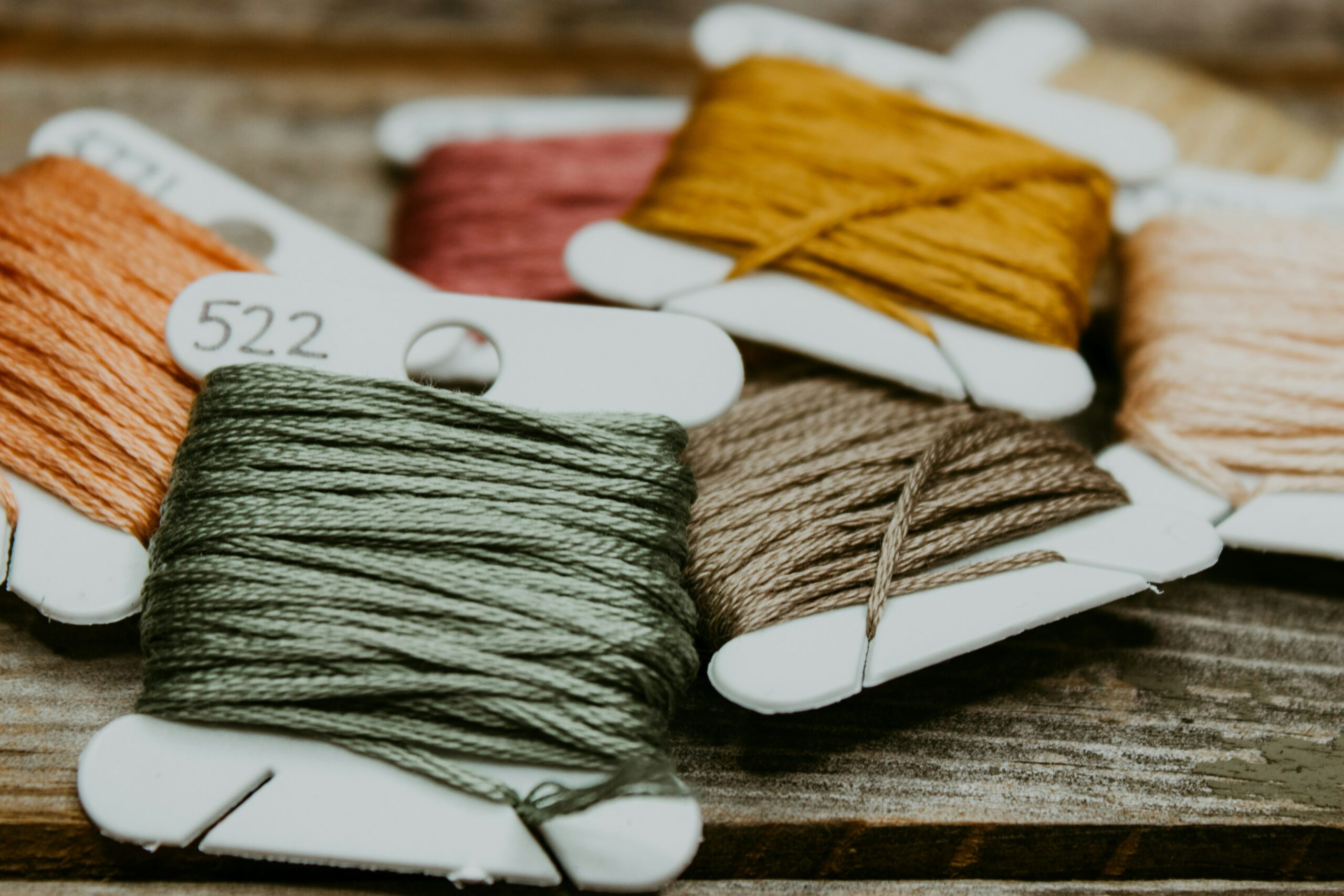 Close-up of colorful embroidery threads neatly wrapped around bobbins, showcasing tools used in craft projects like sewing or embroidery.