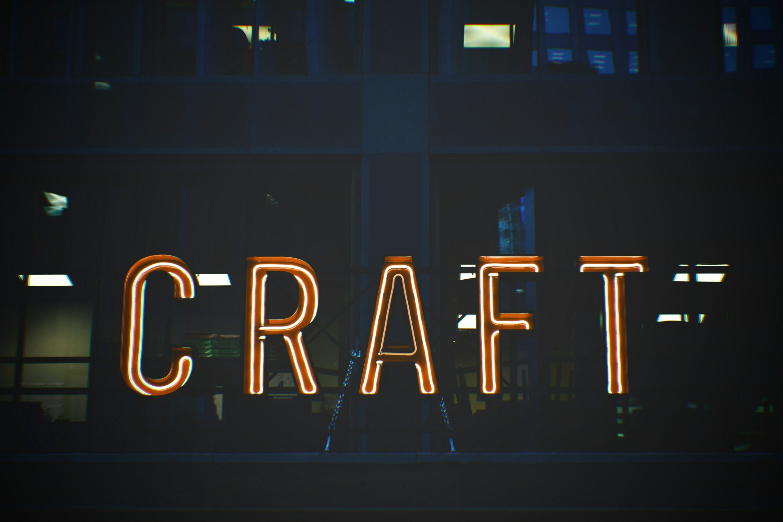 A glowing neon sign spelling out the word "CRAFT" displayed on a dark building background, emphasizing creativity and craftsmanship.