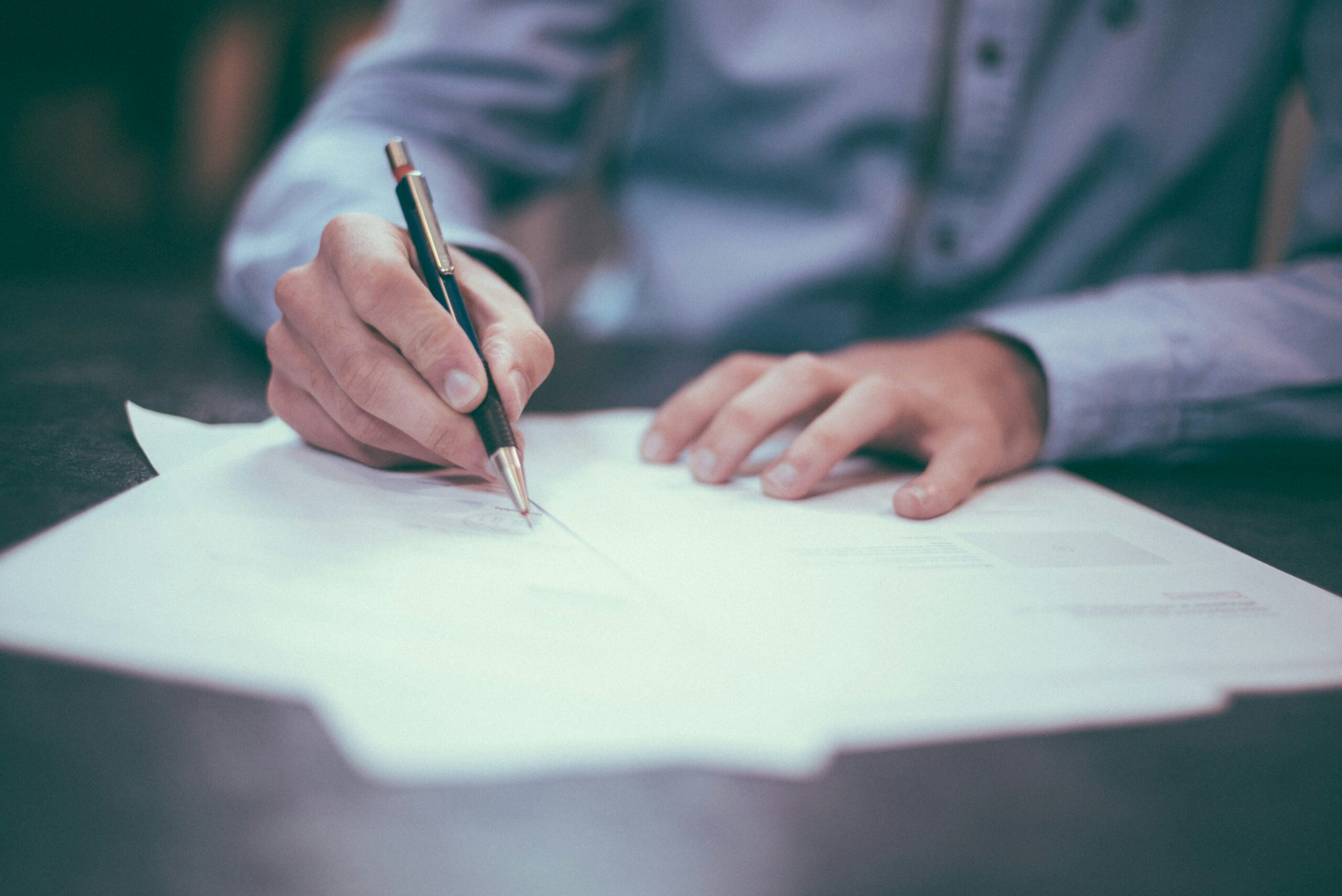 A man, the owner of a candle-making business, diligently writing on a document, likely related to his business operations or inventory.